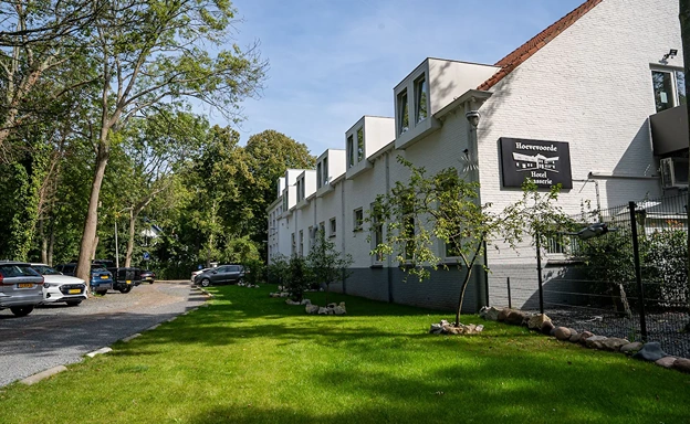 Vooraanzicht van Hotel Hoevevoorde met parkeerplaats en groene omgeving, ideaal voor een bedrijfsuitje met overnachting